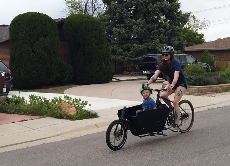 Woman riding an Argo cargo bike with a child in a residential
