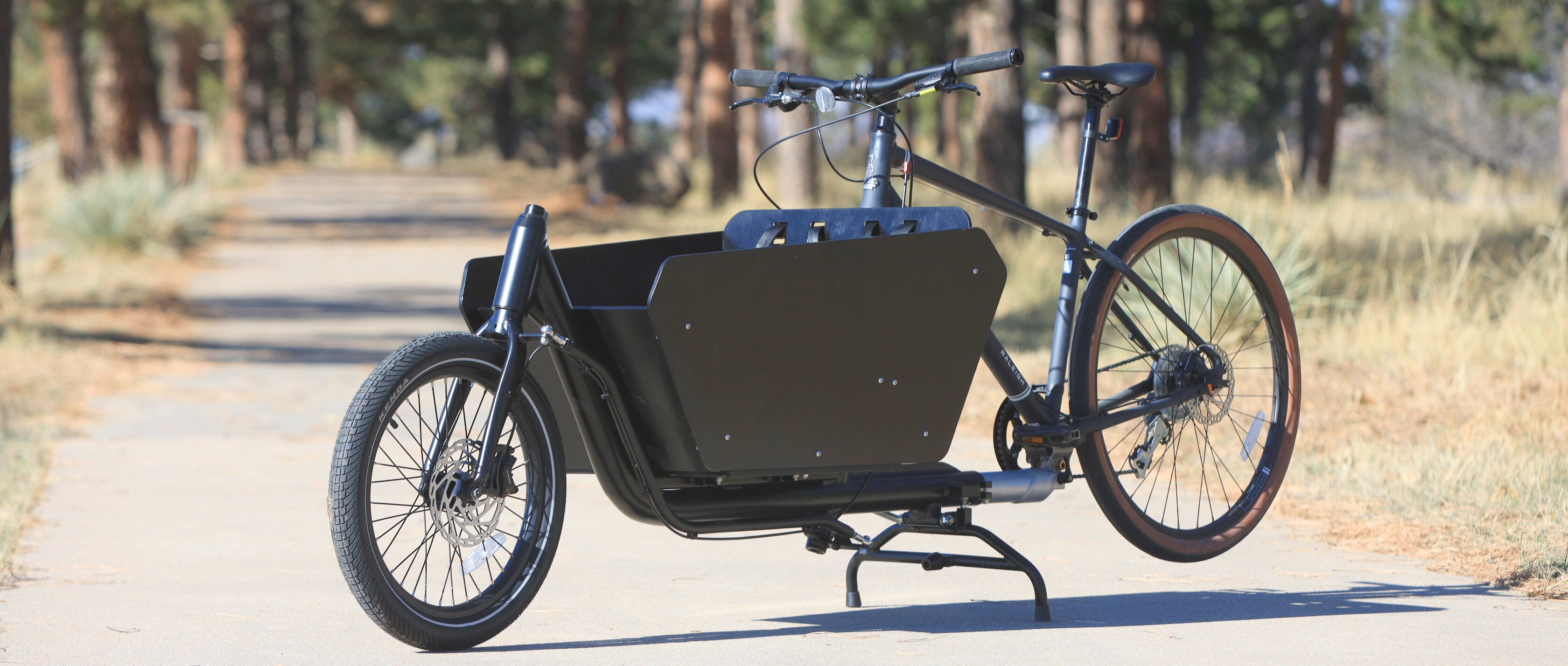 Black Argo cargo bike with a large storage box on a paved path
